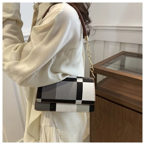 Detail of checkered leather flap bag featuring elegant gold chain and brown leather strap