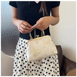 Dettaglio di piccola borsa vintage con catena, motivi di farfalle dorate e chiusura in metallo