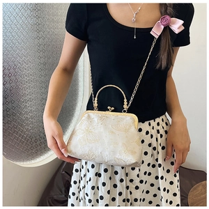 Dettaglio della borsa vintage in raso bianco con ricamo a farfalla dorata e chiusura