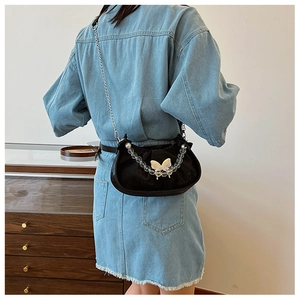 Close-up of black crescent shoulder bag featuring a white butterfly and pearl chain strap