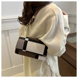 Detail of checkered crossbody bag with gold chain strap worn over the shoulder