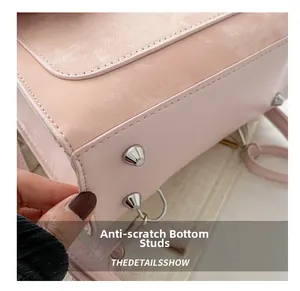 Close-up of pink crossbody bag bottom featuring silver metal feet for wear protection