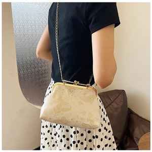Dettaglio della borsa a conchiglia beige in jacquard con farfalla dorata e catenina