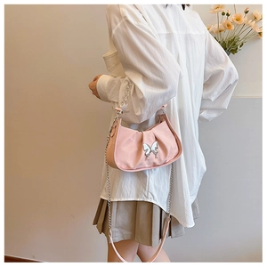 Pink pleated underarm bag with silver butterfly charm and chain strap shown on model