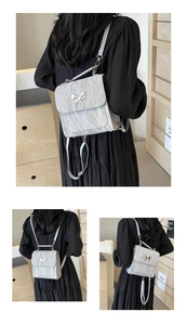 Detail of silver pleated texture and 3D metal butterfly clasp on this crossbody bag