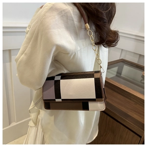 Detail of a color-block underarm bag with metal chain strap worn by a model