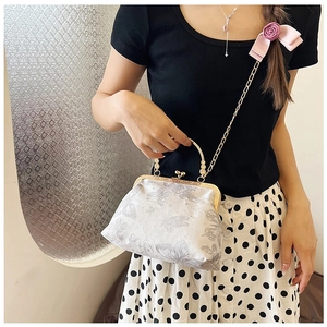 Dettaglio della borsa vintage con telaio metallico, ricamo a farfalla e fiocco rosa