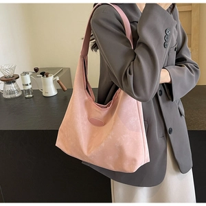 Gros plan sur le sac hobo rose avec texture en daim mat et détail logo elliptique