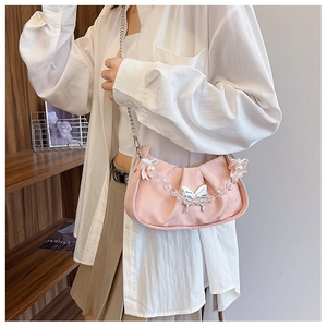 Detail of pink ruched shoulder bag with butterfly metal pendant and pearl chain