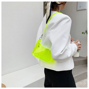 Close-up of a trendy neon green transparent PVC half-moon shoulder bag worn by a model