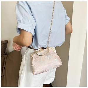 Dettaglio del tessuto jacquard rosa con motivo cinese e tracolla a catena dorata