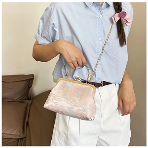 Dettaglio borsa in seta jacquard rosa con motivi paesaggistici e tracolla a catena