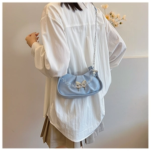 Détail du sac plissé bleu clair avec breloque papillon argentée et poignée en perles