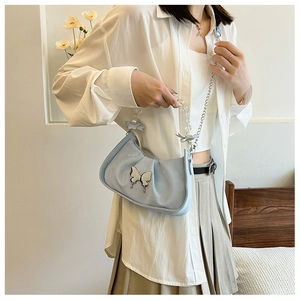 Détail du sac plissé bleu clair avec papillon argenté et poignée en perles