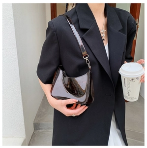 Glossy dark brown faux leather underarm bag held by a model in a black blazer