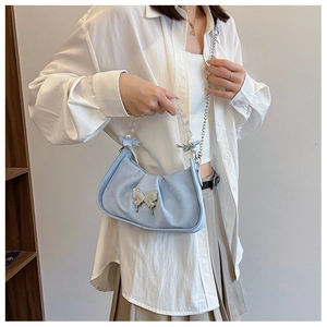 Close-up of light blue pleated handbag featuring a silver butterfly clasp and pearl strap