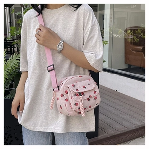 Detail of pink corduroy crossbody bag with red strawberry pattern and adjustable strap