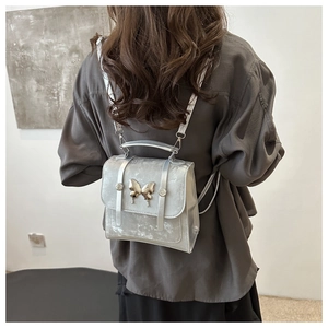 Detail of silver mini backpack showing metal butterfly clasp and sleek matte texture