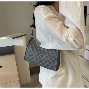 Dettaglio della borsa a mezzaluna grigia a motivi indossata con camicia bianca