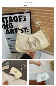 Detail of cream white pleated crescent bag with silver butterfly and beaded handle