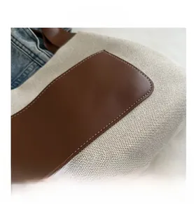 Detail of cream canvas bag with brown leather patch and high-quality stitching