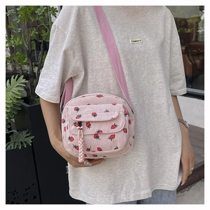 Detailed shot of pink corduroy crossbody bag with cute strawberry pattern print