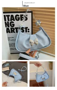 Close-up of blue crescent bag with golden butterfly buckle and pearl beaded handle
