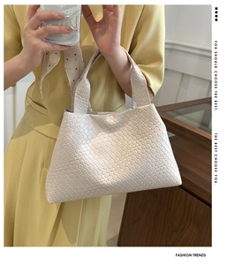 Detail of cream white woven tote bag showing the classic leather craftsmanship and texture
