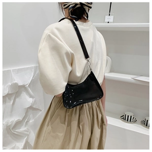 Detail showing the glossy black patent leather surface and silver hardware of the underarm bag