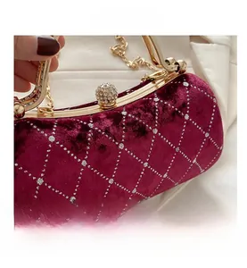 Detail of burgundy velvet handbag with silver diamond lattice and gold spherical clasp