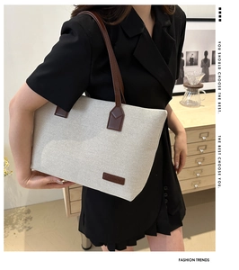 Detail of minimalist cream canvas tote bag with brown leather straps and fashion label