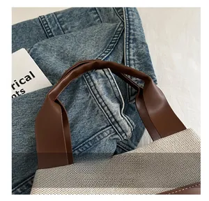 Detail of the brown leather handles and beige woven texture on the fashion bucket bag