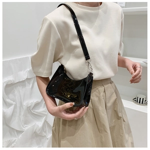 Detail shot of a black glossy patent leather shoulder bag with sleek silver hardware