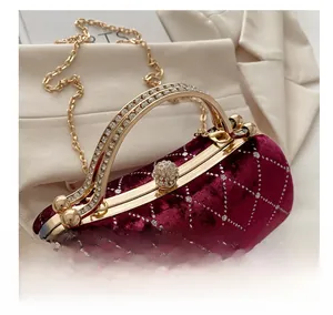 Detailed macro view of burgundy velvet handbag with rhinestone handle and sequin patterns