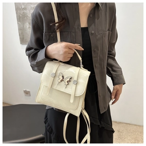 Detail of cream white leather handbag featuring a silver metal butterfly buckle closure