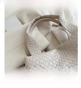 Close-up of beige woven texture and integrated handle on a luxury tote bag