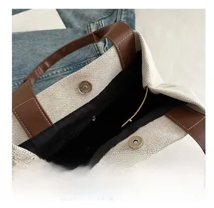 Detail of canvas tote bag showing magnetic clasp, leather handle, and interior pocket