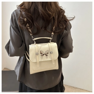 Detail view of cream PU leather mini backpack with silver metal butterfly decoration