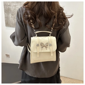 Detailed view of creamy white leather backpack with large silver metal butterfly buckle