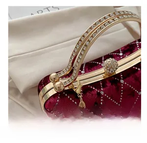 Detailed macro view of burgundy velvet handbag with sparkling rhinestone handle and clasp