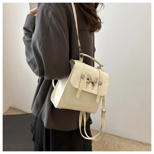 Detail of cream leather backpack with silver butterfly charm and retro buckle closure