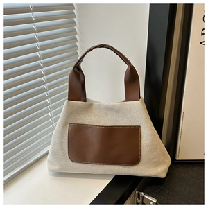 Close-up of canvas stitching and brown leather pocket detail on bucket handbag