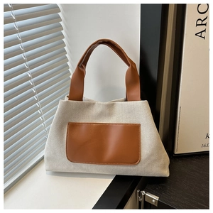 Detail of contrast color canvas tote bag showing cream fabric and brown PU leather handles