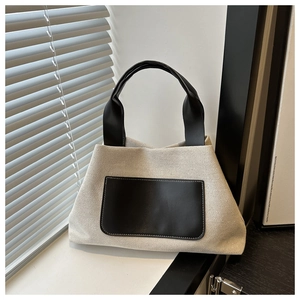 Detailed texture of off-white canvas and black leather accents on a stylish bucket bag