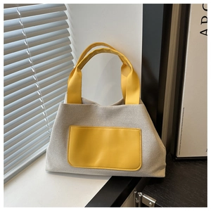 Detail of grey woven canvas tote bag featuring vibrant yellow handles and a contrast pocket