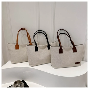 Three minimalist canvas tote bags with leather handles in beige, black, and brown