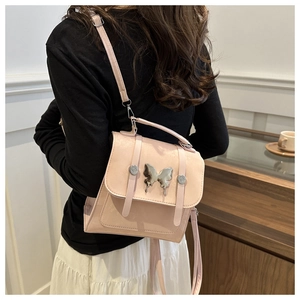 Detailed view of a pink crossbody bag featuring a silver butterfly clasp and leather texture