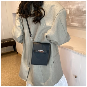 Vertical black crossbody phone bag with silver twist lock shown on a female model
