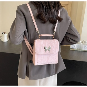 Detail of pink pleated PU leather backpack with silver butterfly accent on model
