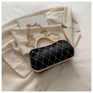 Detailed view of black velvet handbag with golden handle and sparkling diamond lattice pattern
